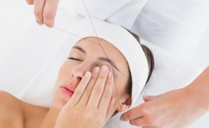 Close up of a hands threading beautiful woman's eyebrow